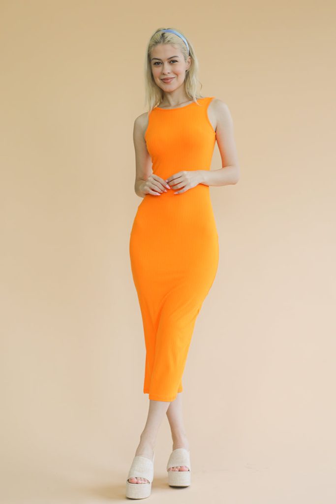 A woman stands against a neutral wall wearing the Her Thread black ribbed sleeveless maxi dress, which is a bodycon style with a stretch-ribbed texture and a floor-skimming length.
