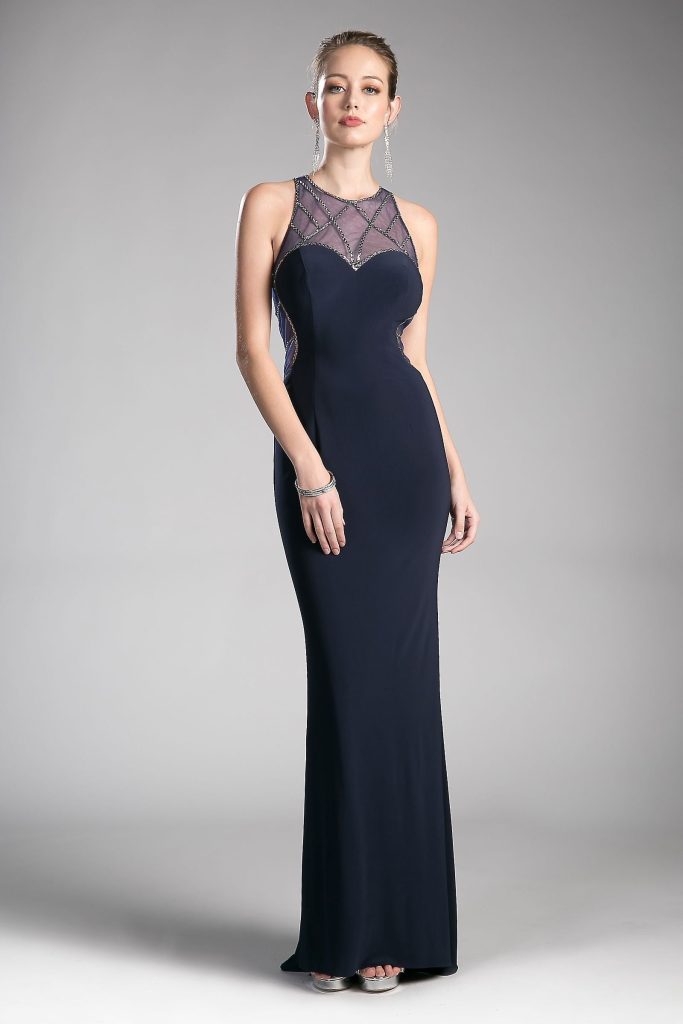 A model wearing a navy beaded jersey gown with a detailed halter neckline, side illusion cutouts, and a flowing skirt, perfect for a formal event.